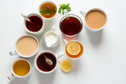 multiple white mugs filled with tea and coffee