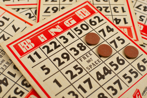 a pile of Bingo boards with 3 bingo chips on top