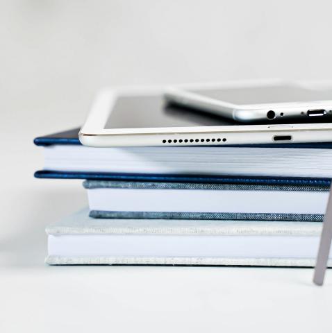 a phone and tablet on top of a stack of books