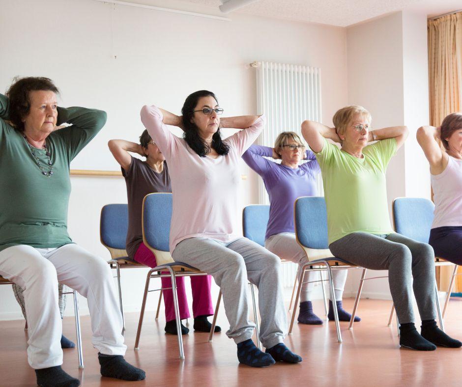 Class of yoga students using chairs for poses